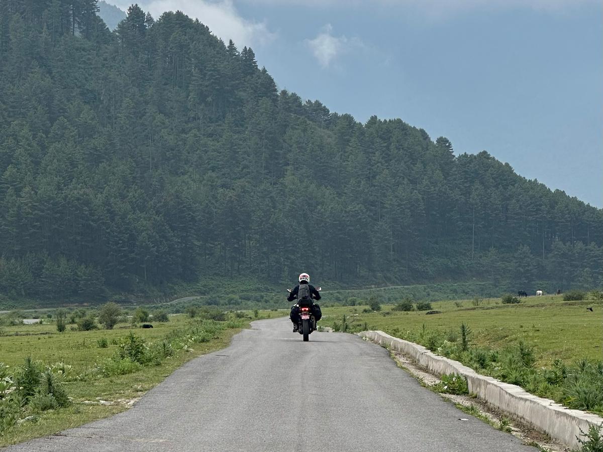 A person on a motorcycle riding down a road in a mountainous area