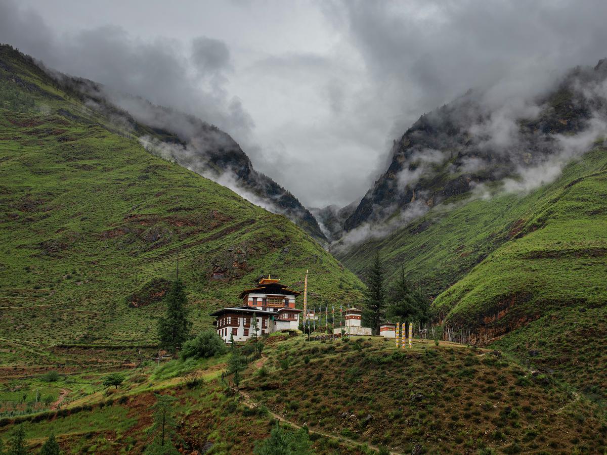 A Bhutanese monastery perched on a mountain, surrounded by greenery and clouds
