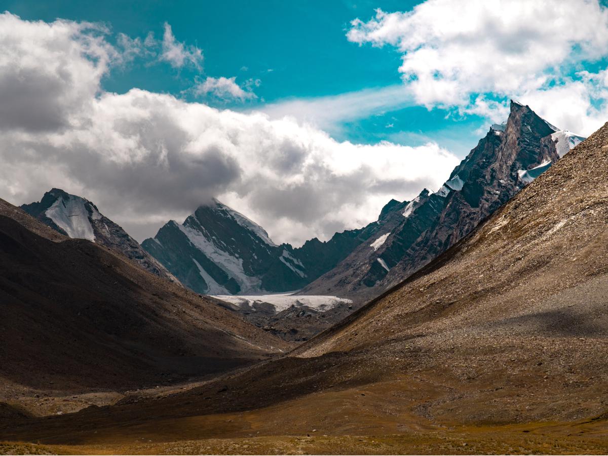 A mountainous landscape with snow-capped peaks and a valley in the foreground.