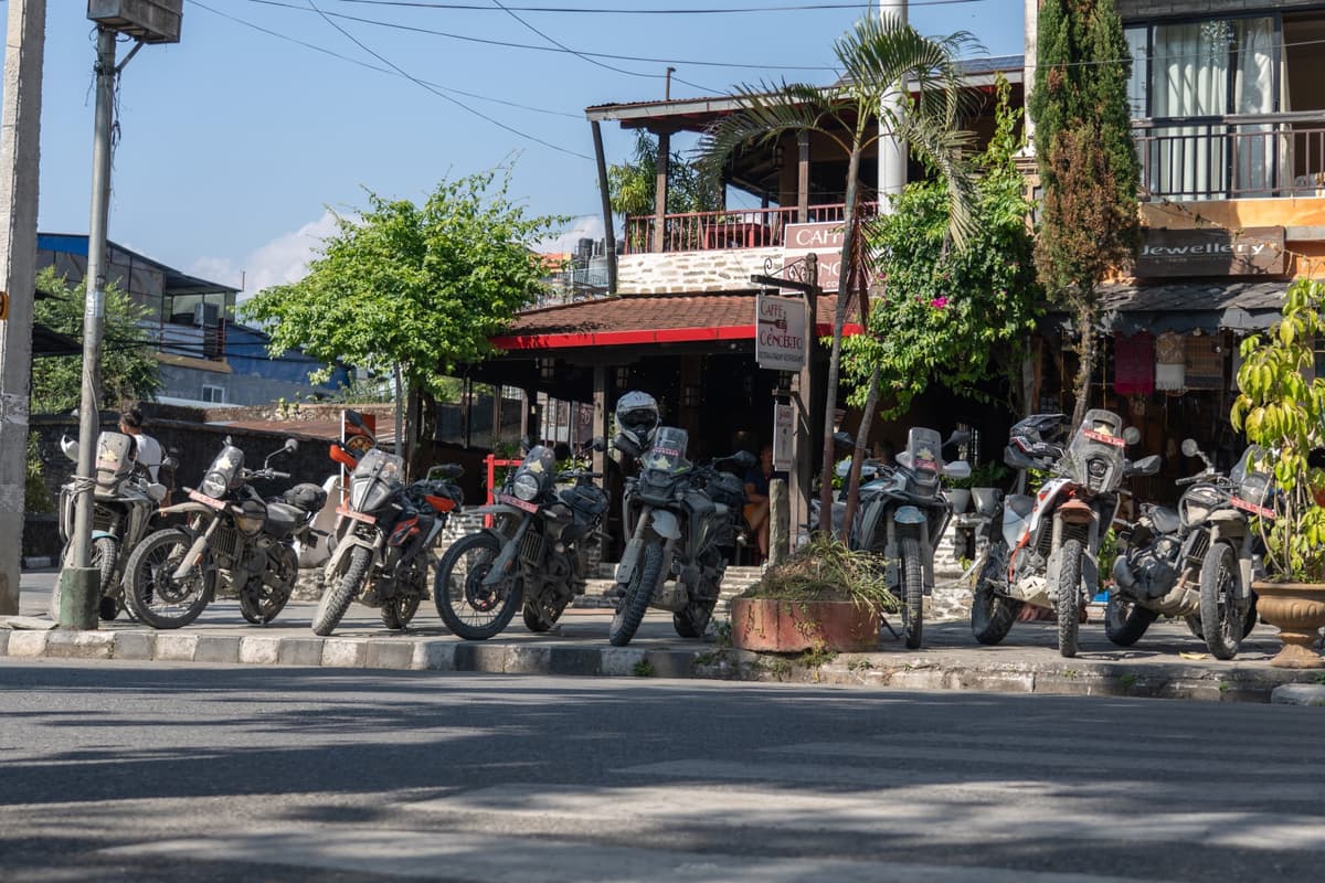 Row of adventure motorcycles parked outside a café on a street during our Nepal motorcycle tour.