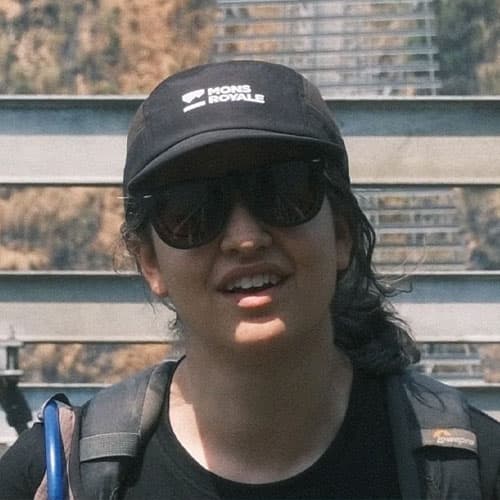 Portrait of Saris M wearing a black cap, sunglasses, and backpack straps, smiling during our motorcycle tour.